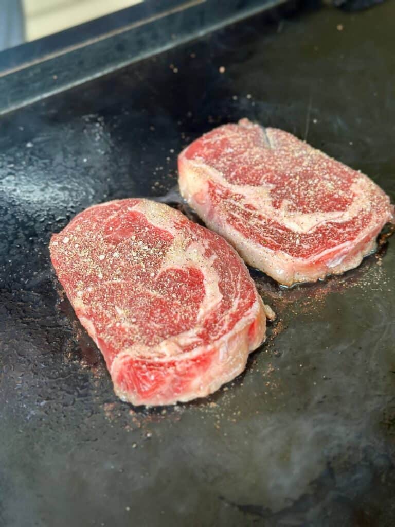 searing ribeye steaks on a griddle