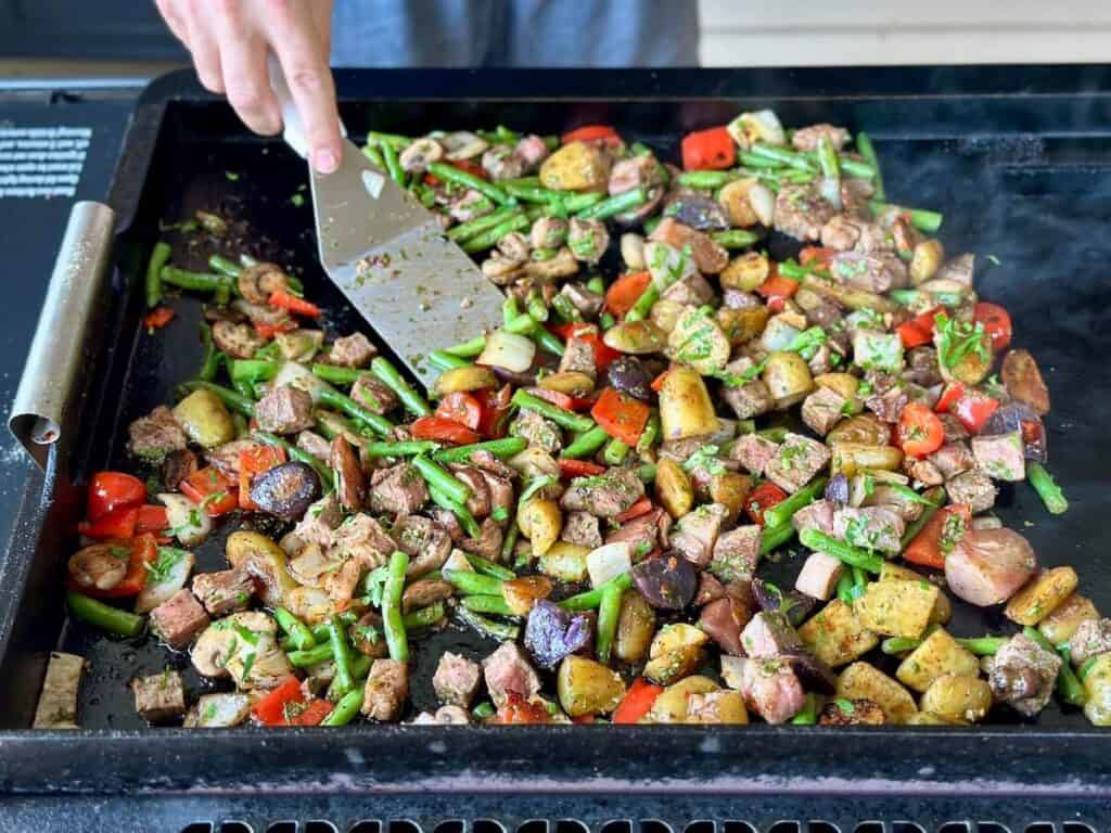 making a steak stir fry with chimichurri sauce on the griddle