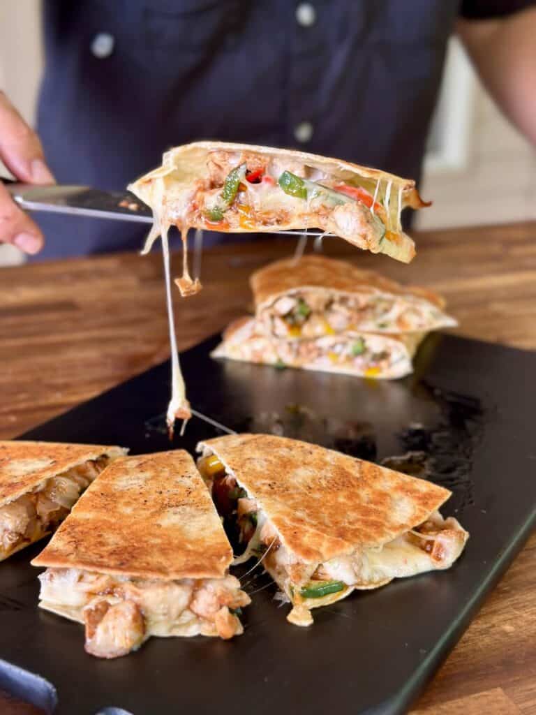 cutting a chicken fajita quesadilla with melty cheese