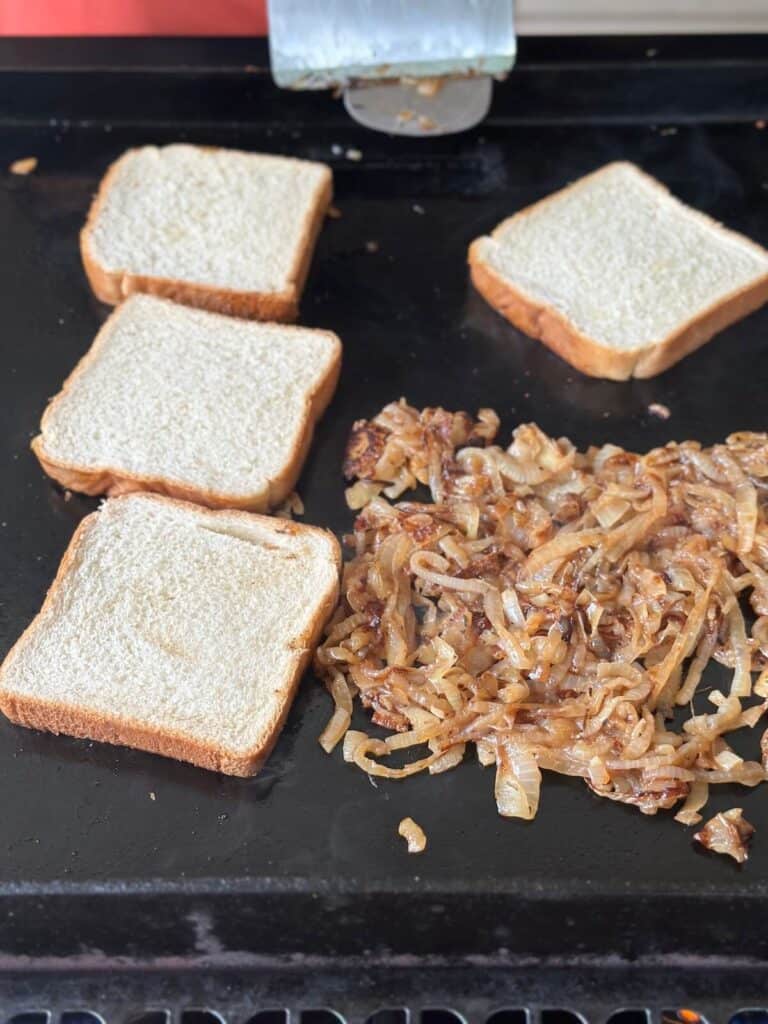 toasting bread on a griddle while cooking onions