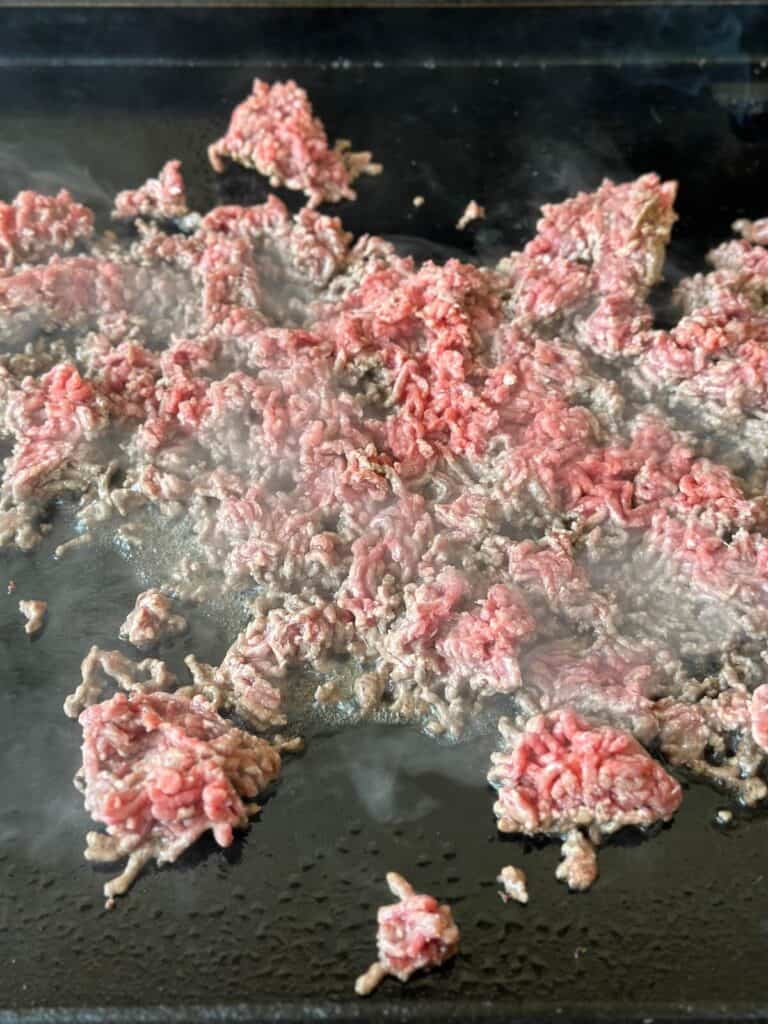 cooking ground beef on the griddle for tacos