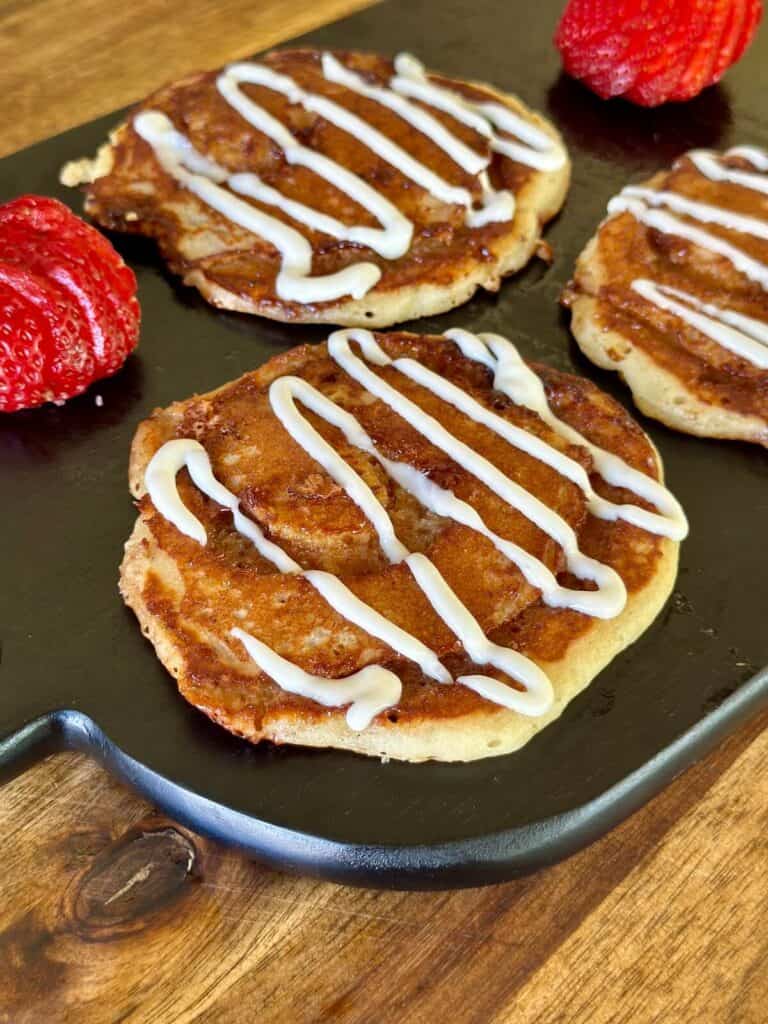 cinnamon roll pancakes with cream cheese glaze drizzled on top