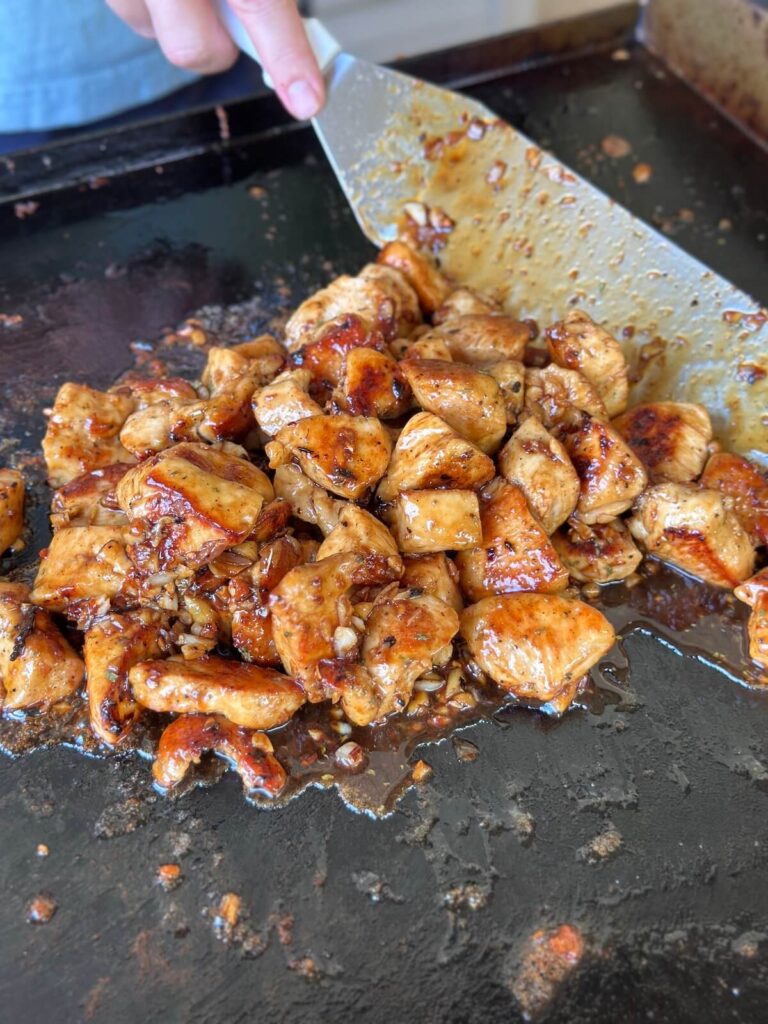 cooking honey garlic chicken bites on a Blackstone griddle