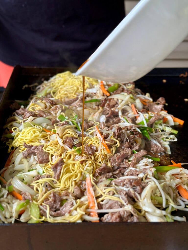 adding chow mein sauce to beef and chow mein noodles