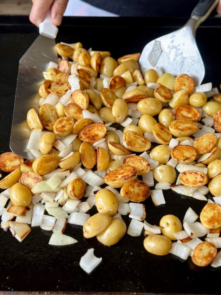 cooking cut onions and potatoes on Blackstone griddle
