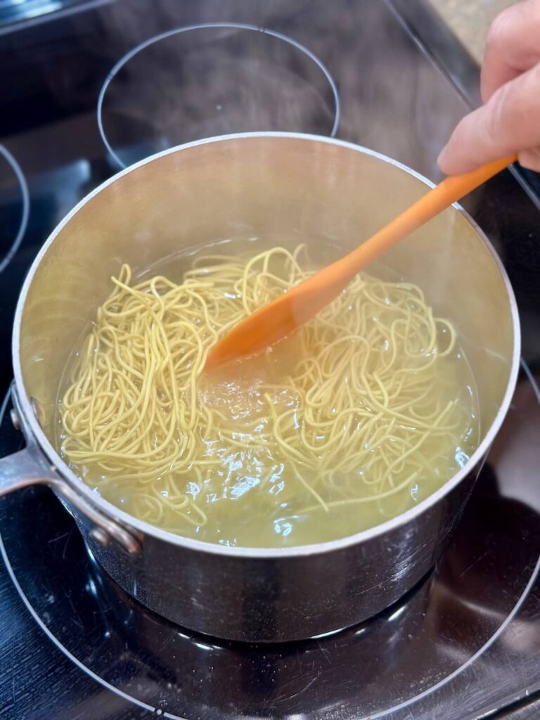 boiling chow mein noodles on a stovetop