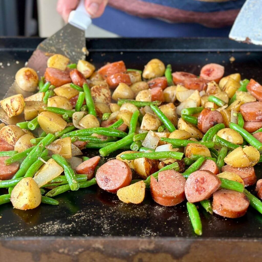 cooking smoked sausage and potatoes on a Blackstone griddle