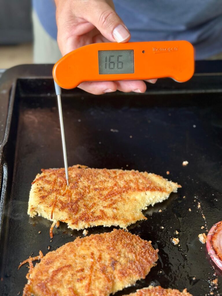 instant read probe thermometer to check the temperature of chicken breast cooking on the griddle