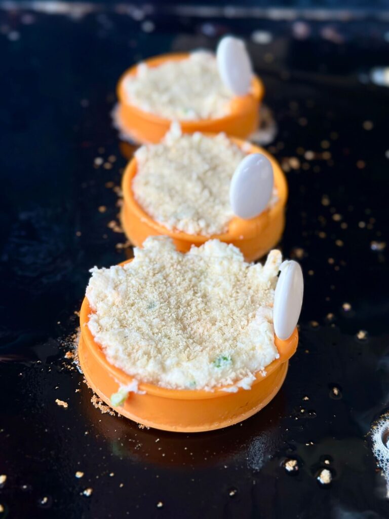making cheesy potato cakes in egg molds on a griddle