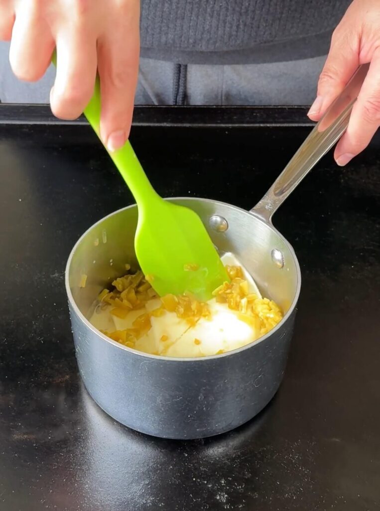 mixing American cheese slices, half and half, and diced green chiles in a small pot