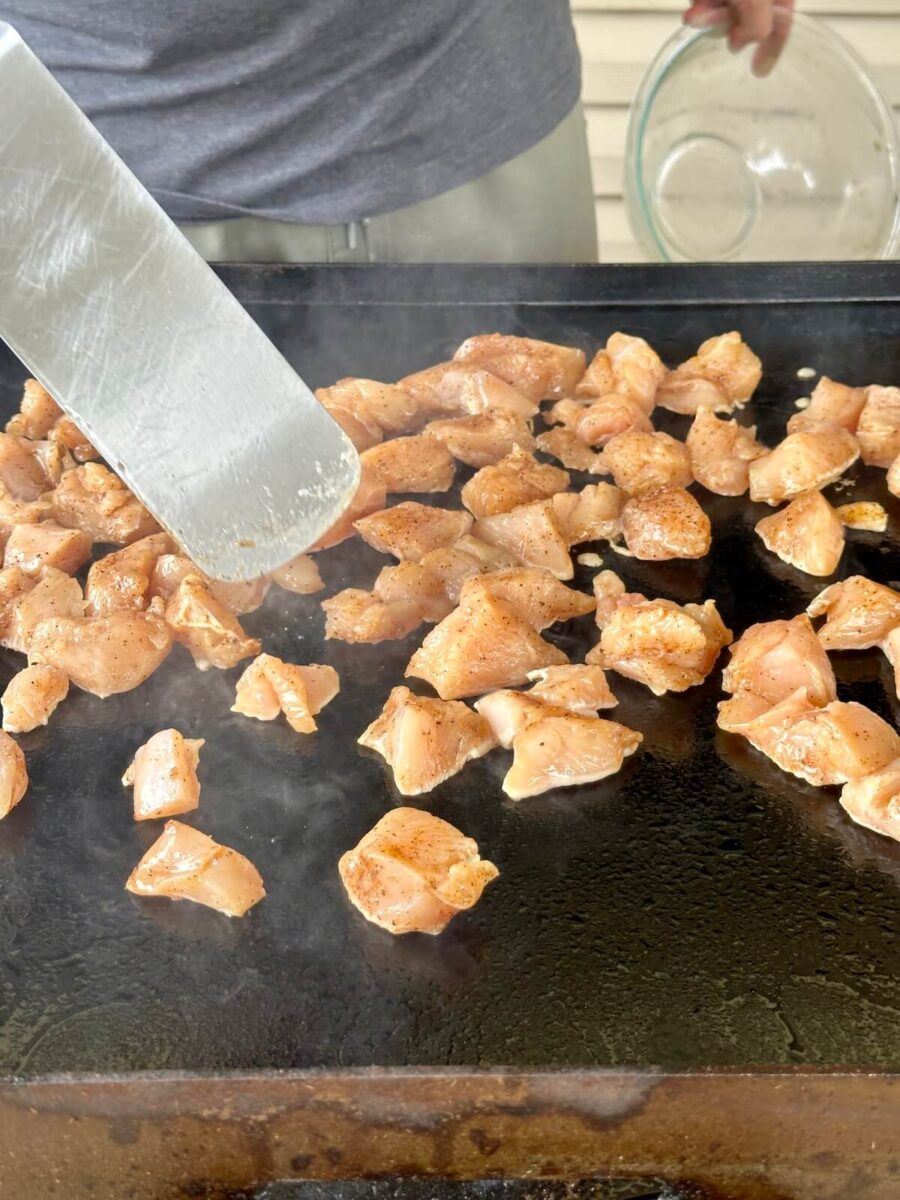using a spatula to flip chicken bites on a griddle
