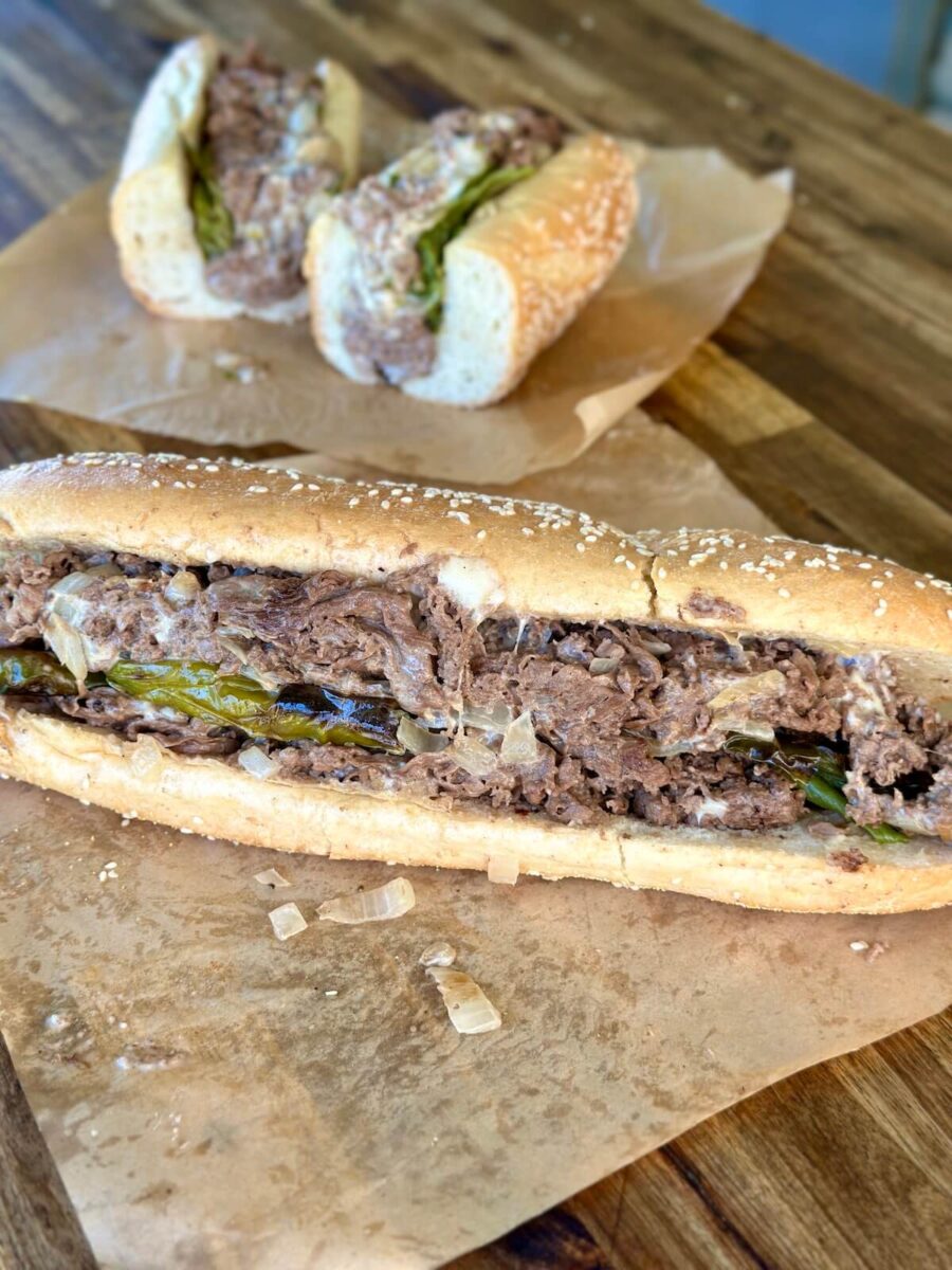 a Philly cheesesteak with long hots peppers wrapped in deli paper