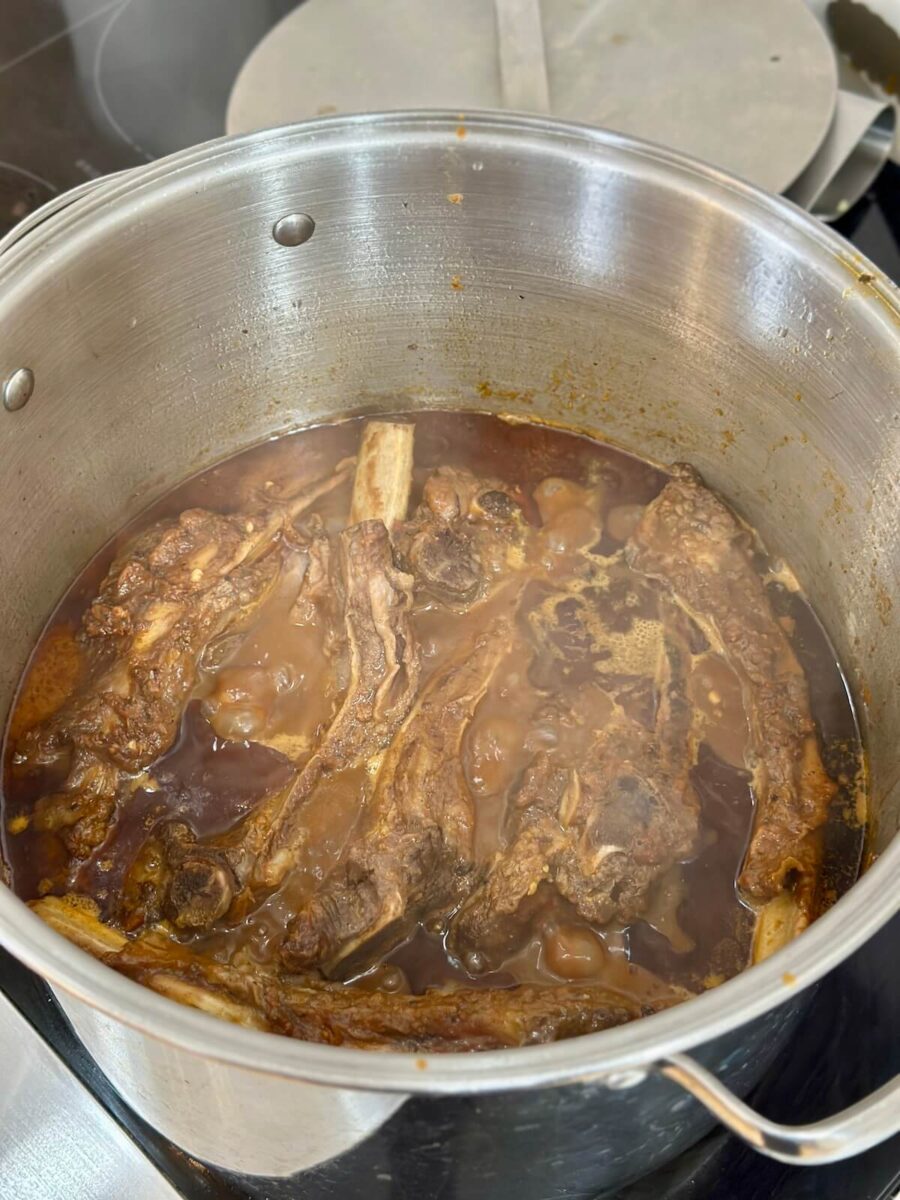 braising chuck roast and beef ribs in a birria sauce in a stock pot