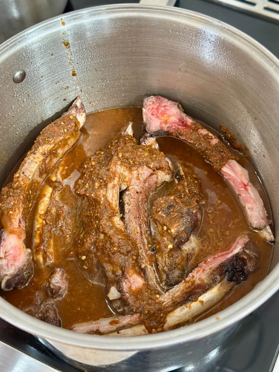 braising chuck roast and beef ribs in a birria sauce in a stock pot
