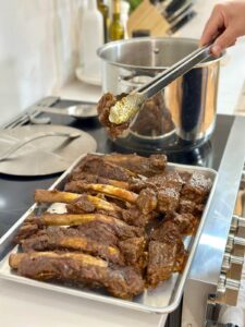 removing chunks of braised chuck roast and beef ribs from a stock pot after cooking