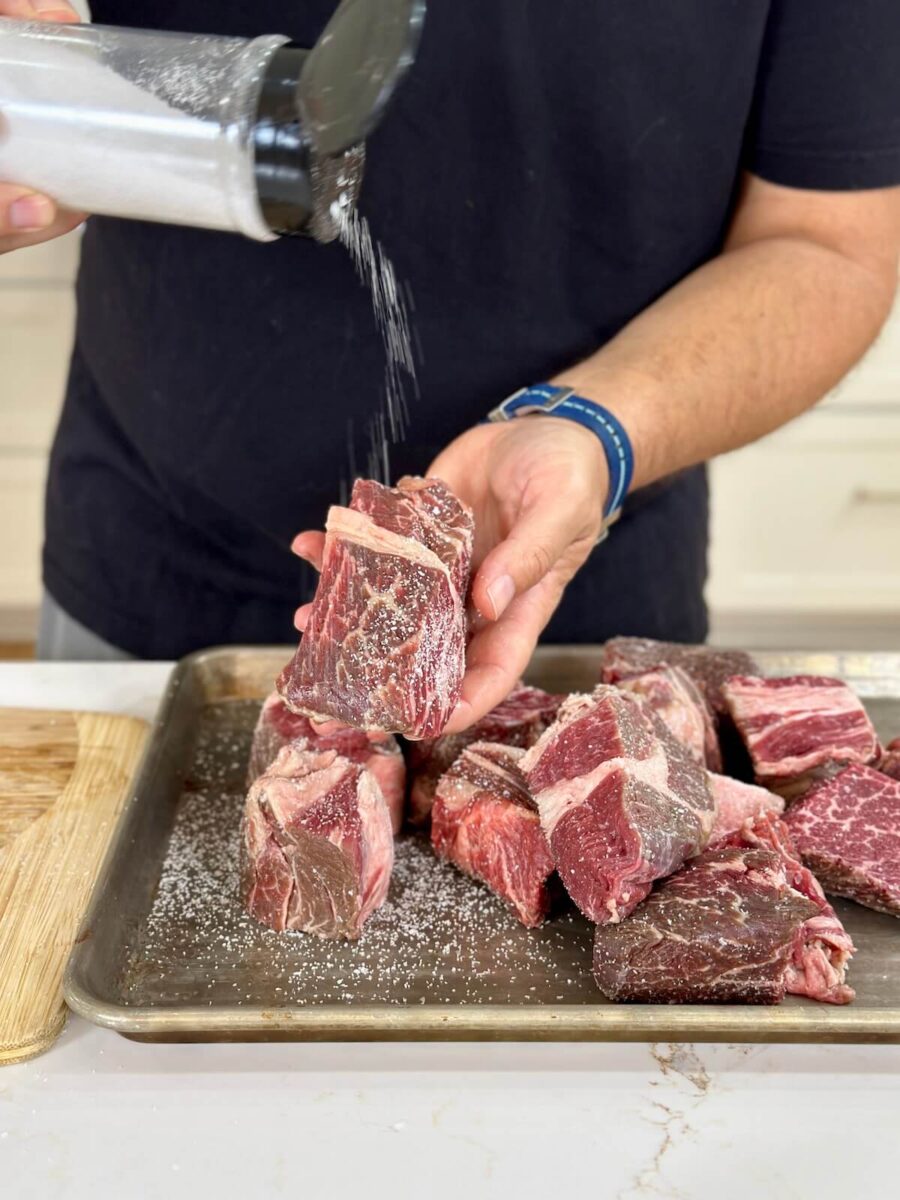 seasoning chunks of beef chuck roast with kosher salt