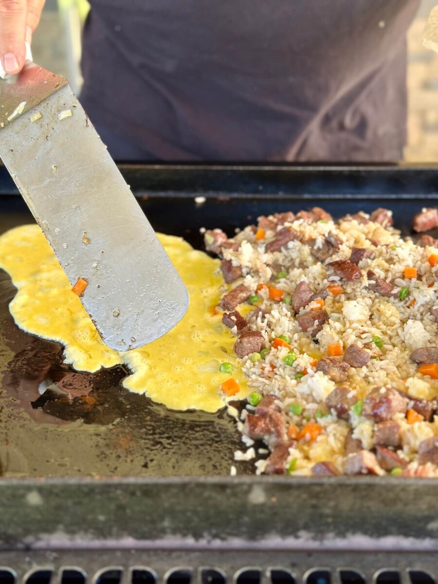 cooking scrambled eggs and steak fried rice on a Blackstone griddle