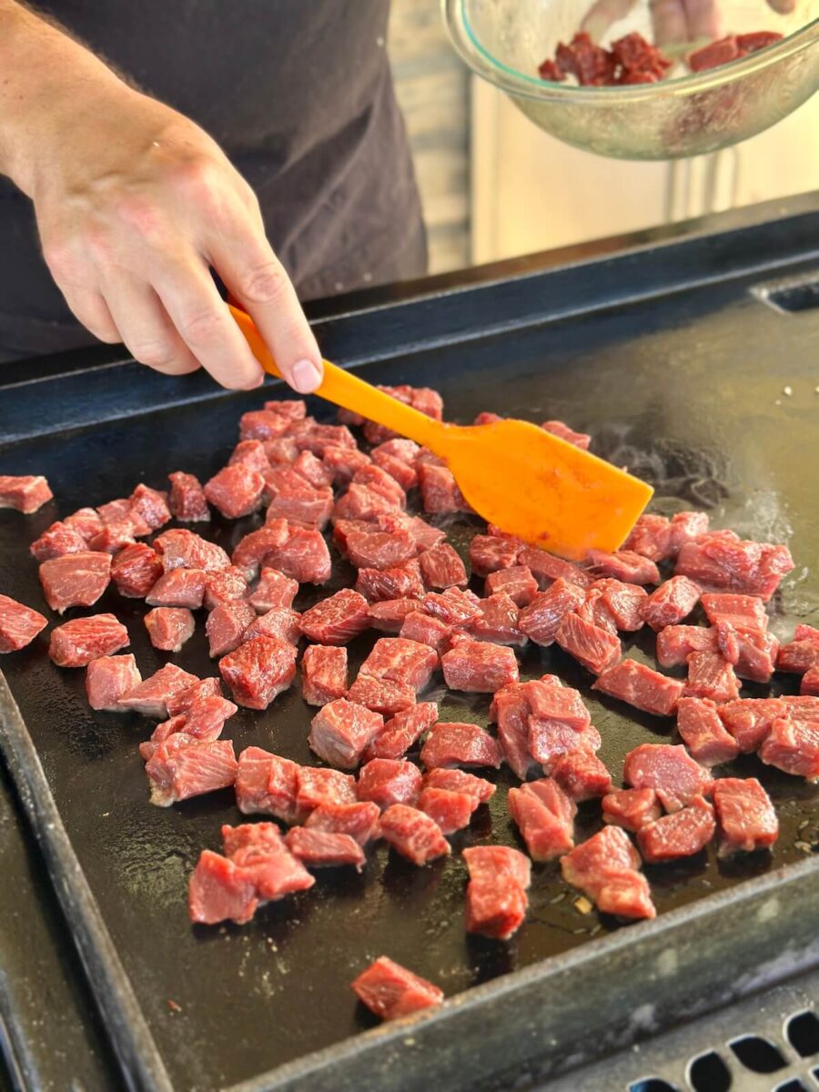 searing cubes of steak on a griddle