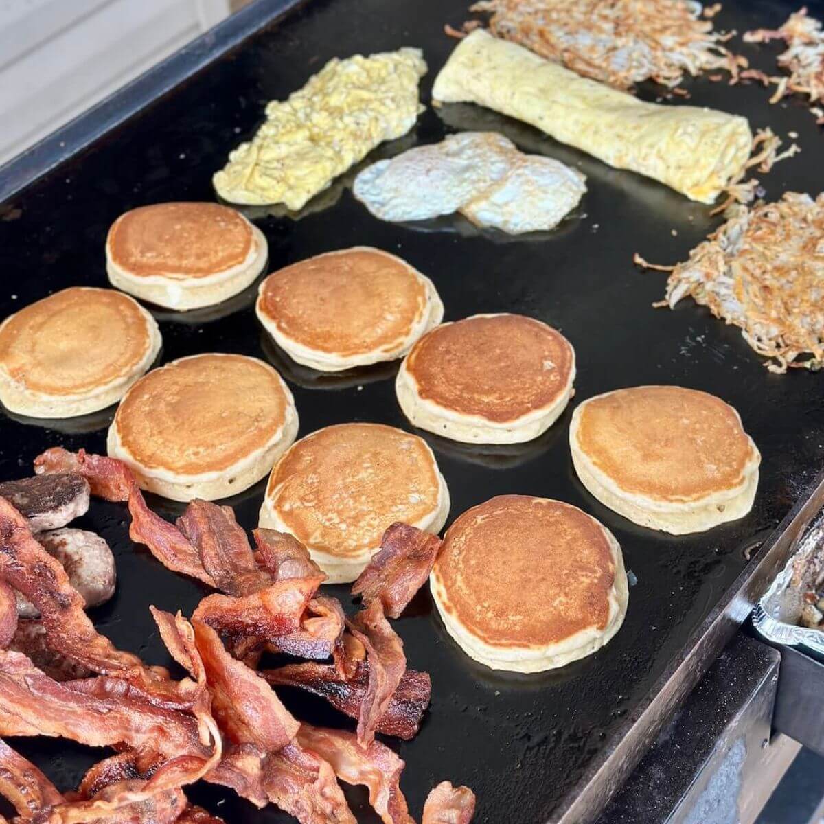 cooking a big breakfast on a Blackstone griddle with bacon, pancakes, hash browns, eggs, and omelettes