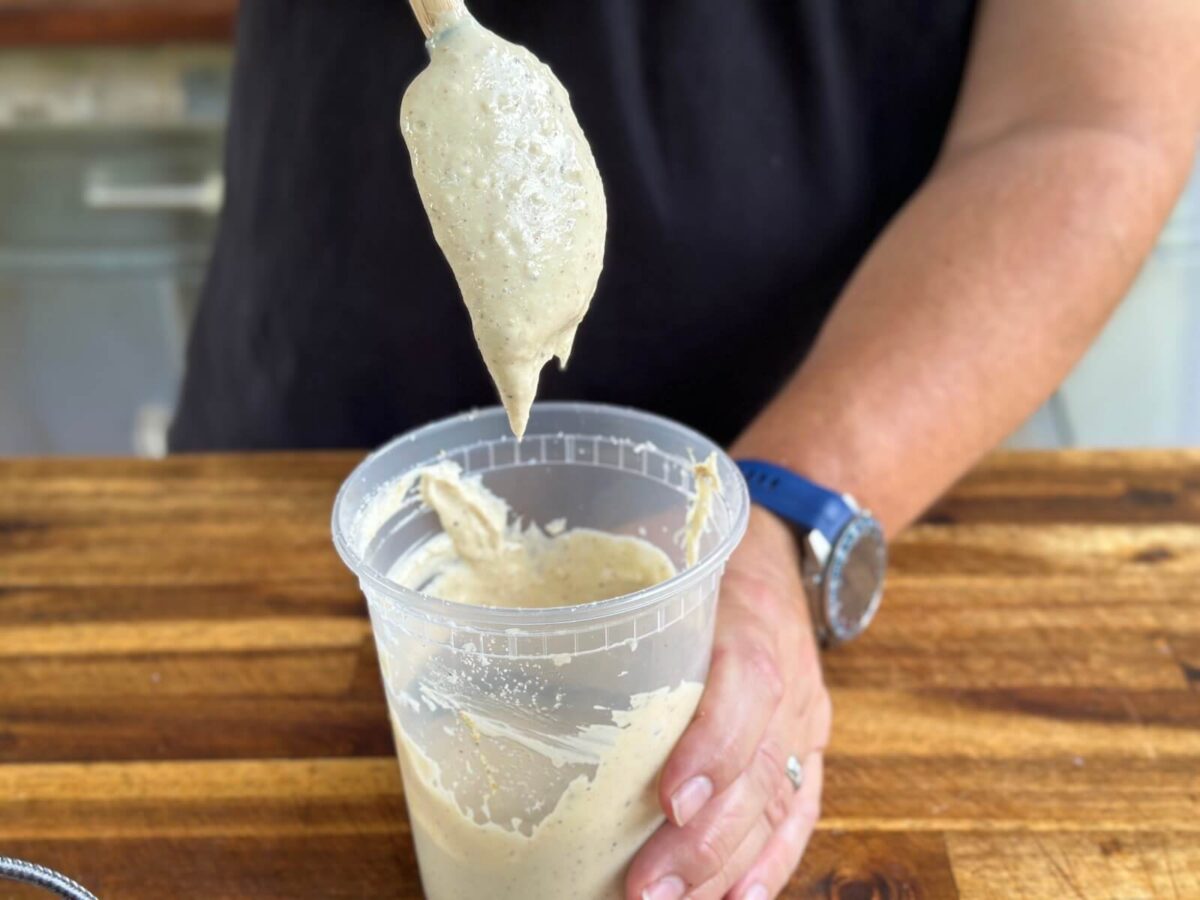 folding parmesan cheese into Caesar dressing in a tall prep container