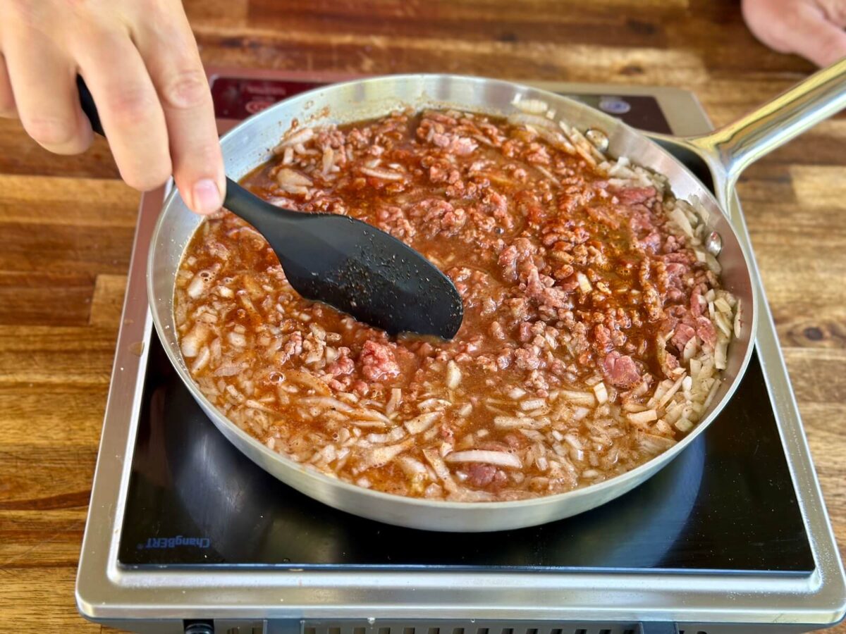 cooking ground beef, diced onion, beef stock, and spices together in a skillet