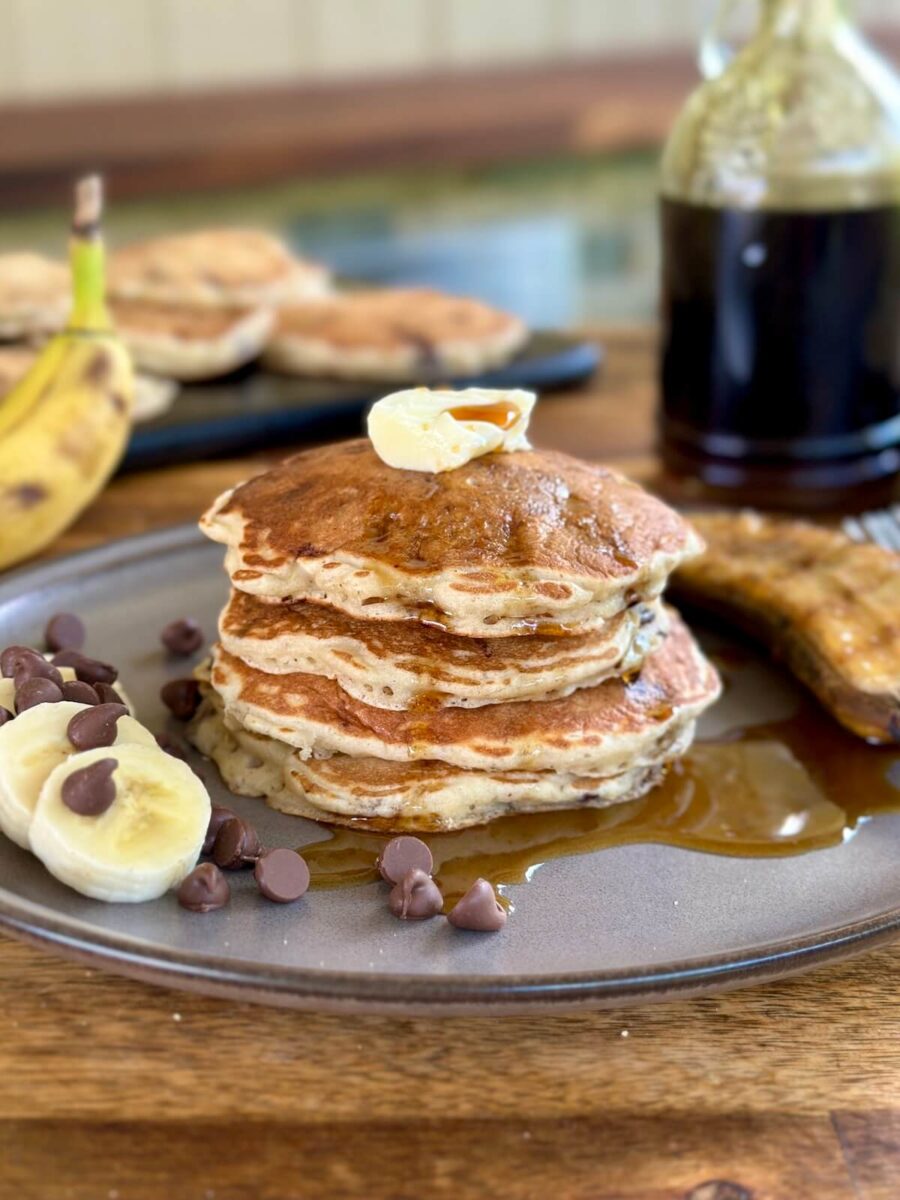 banana chocolate chip pancakes with syrup and butter on a plate