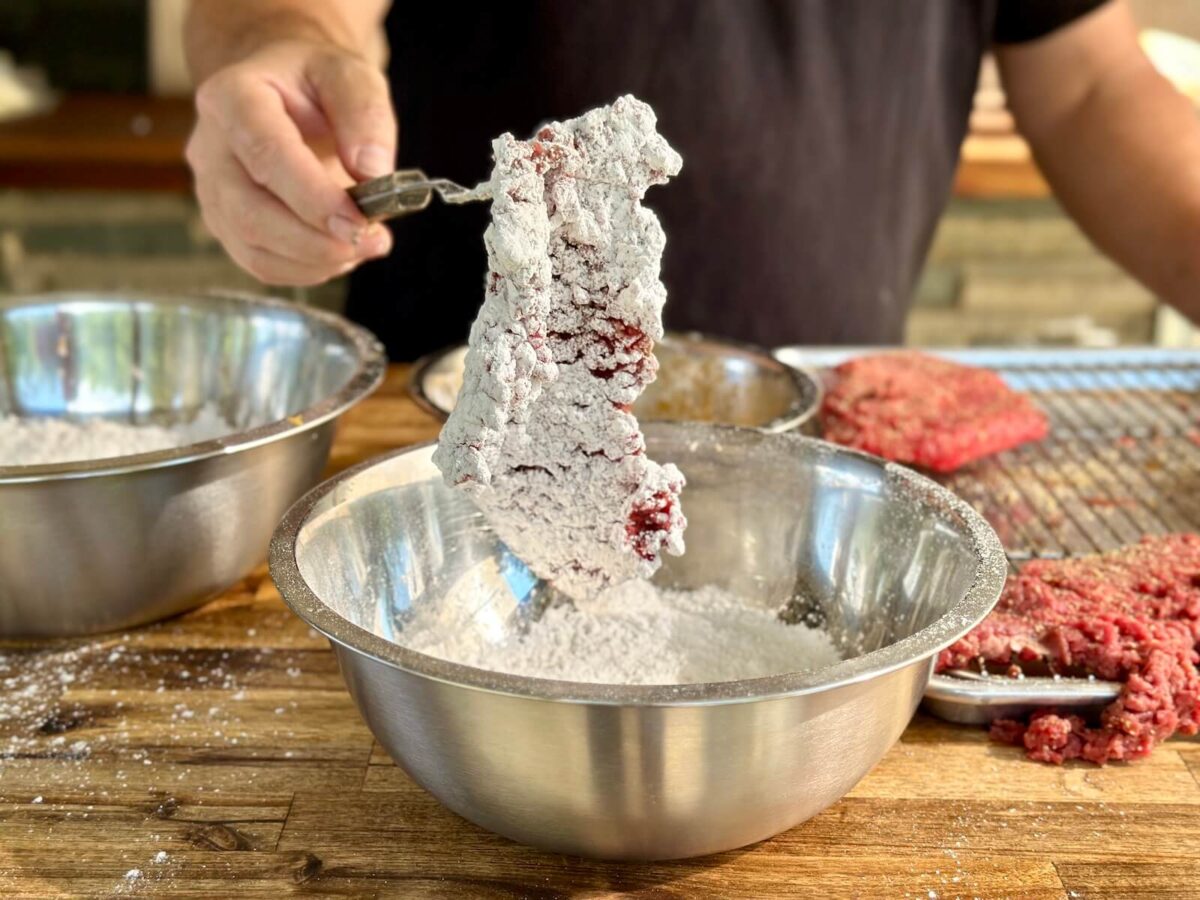 coating a piece of cube steak in flour