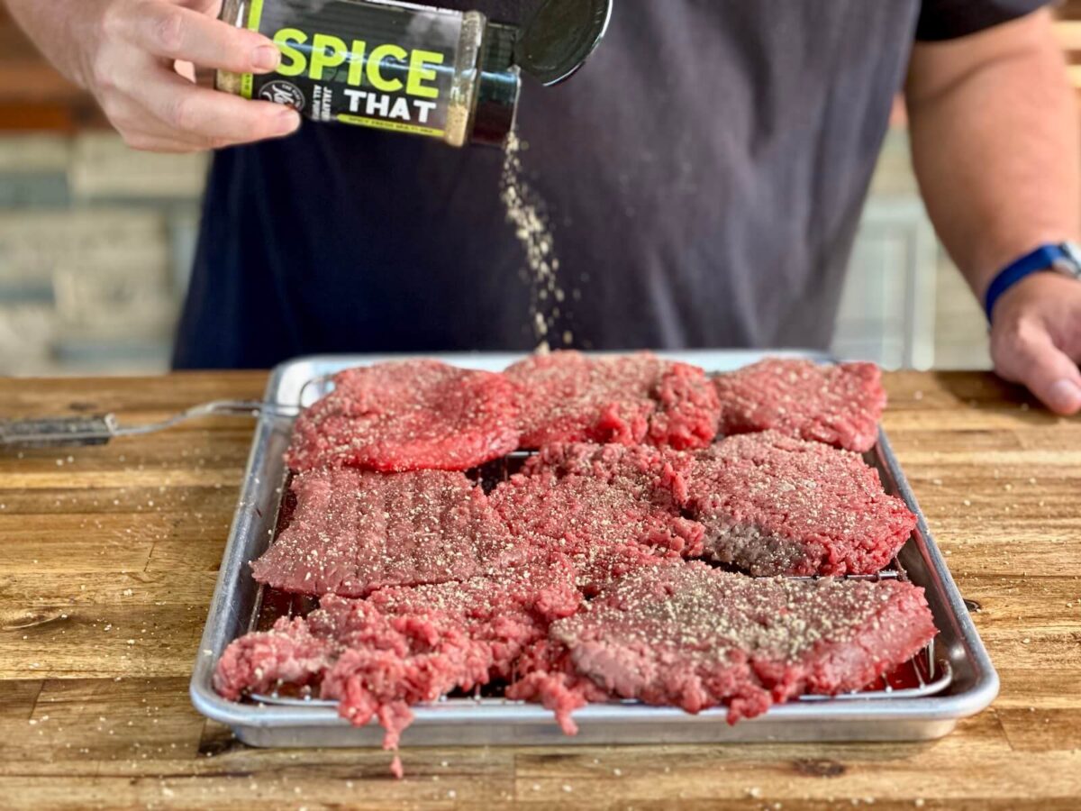 seasoning pieces of cube steak with Spice That seasoning