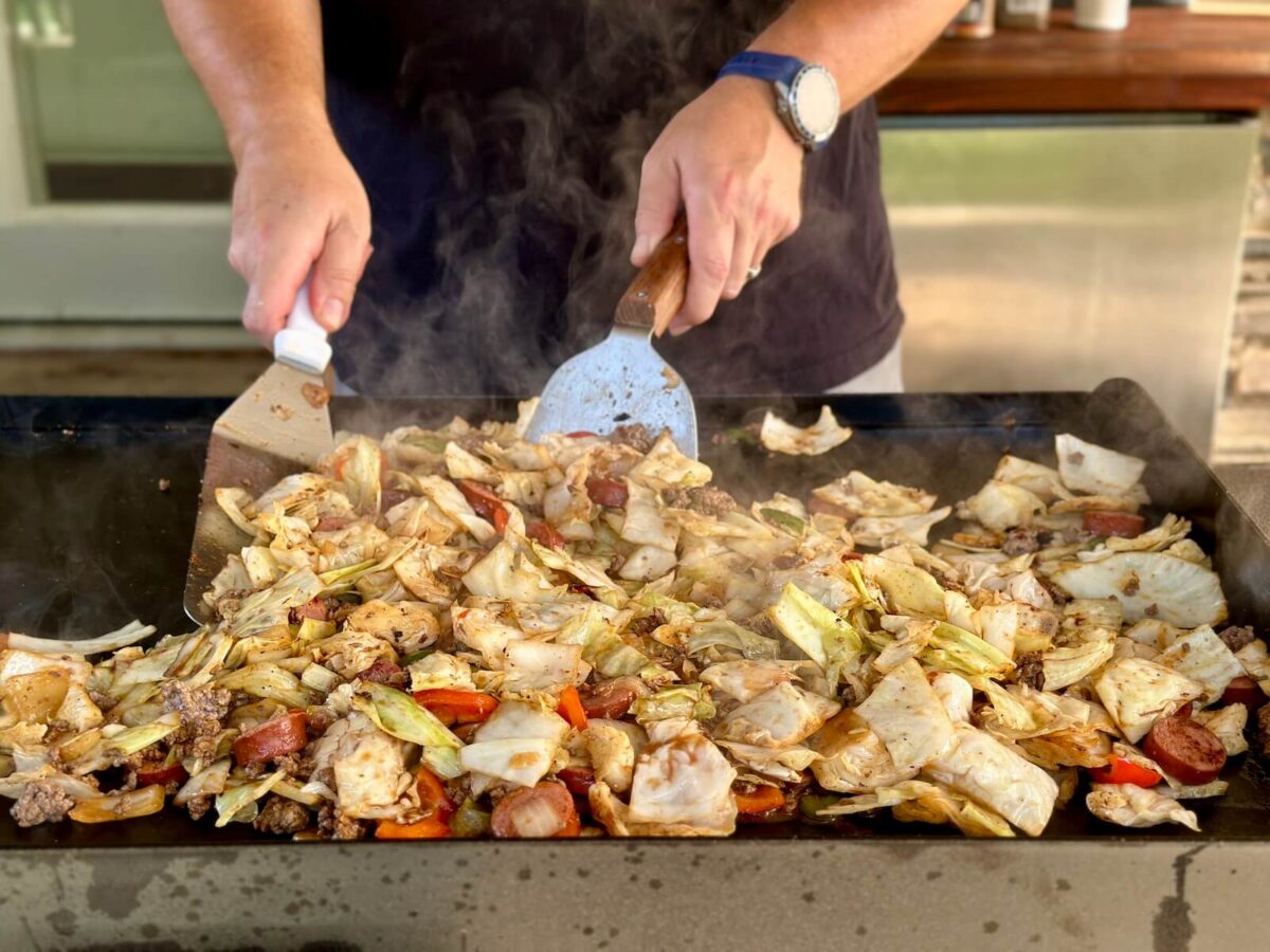 cooking dirty cabbage with sautéed cabbage, ground beef, and vegetables on a griddle