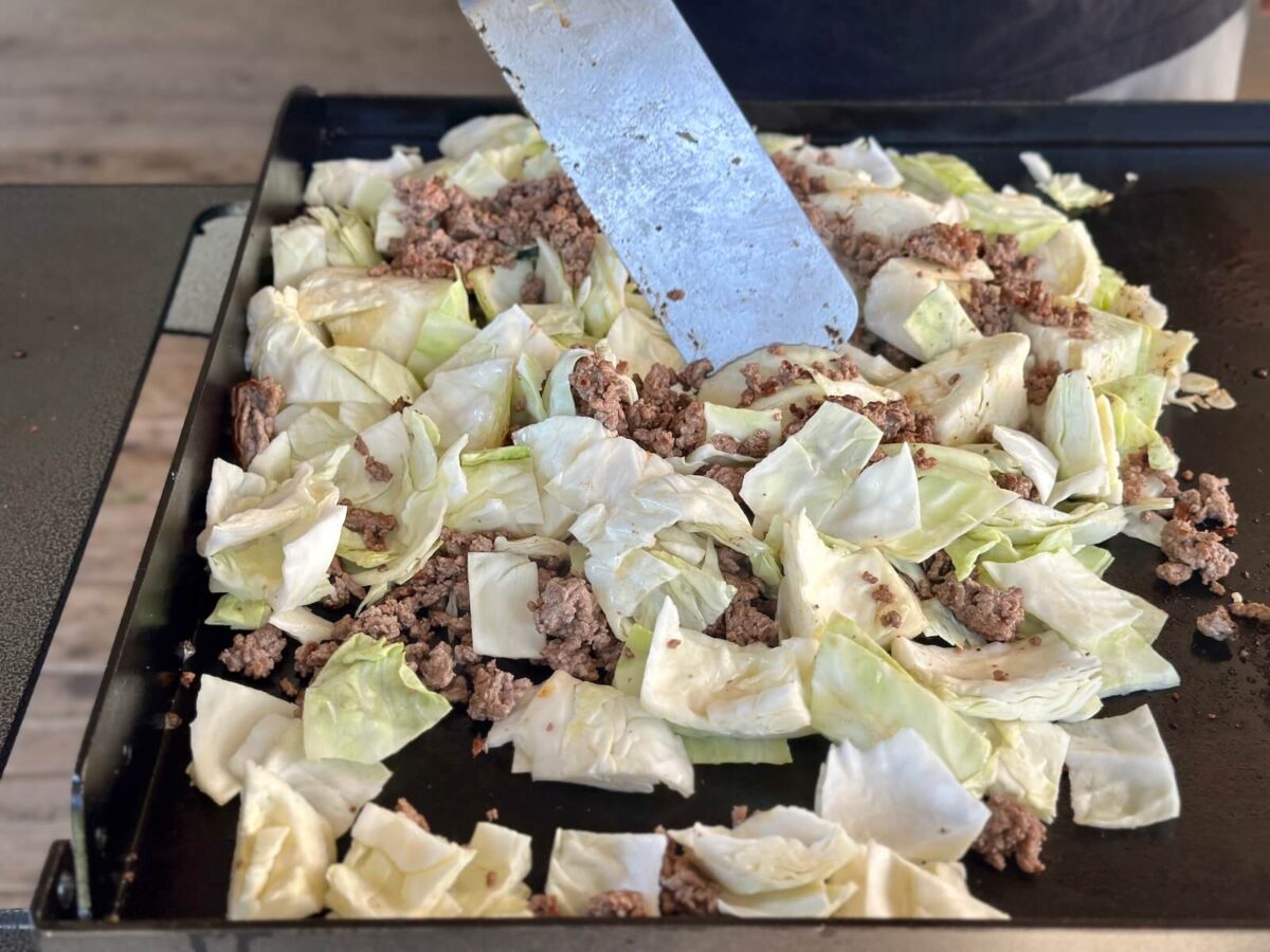 sautéing ground beef and cabbage together on a Blackstone griddle