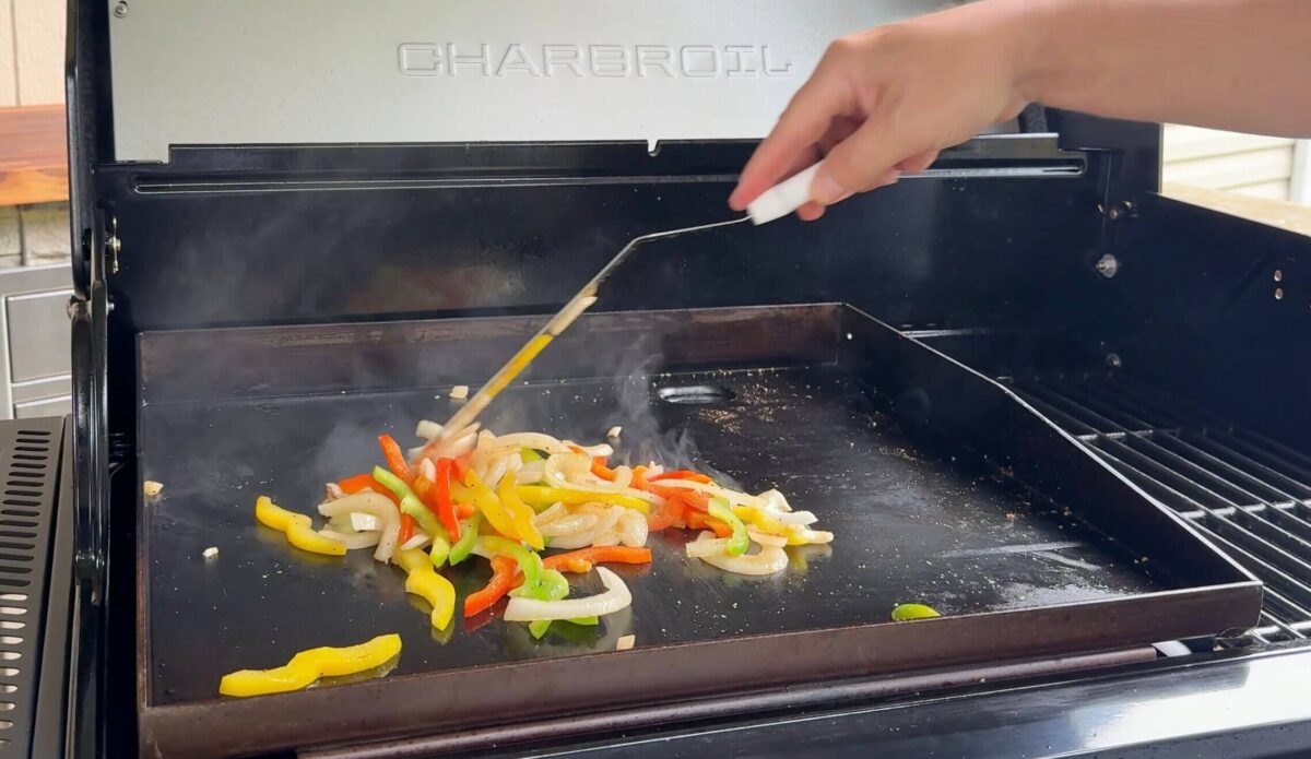 cooking sliced bell peppers on a griddle