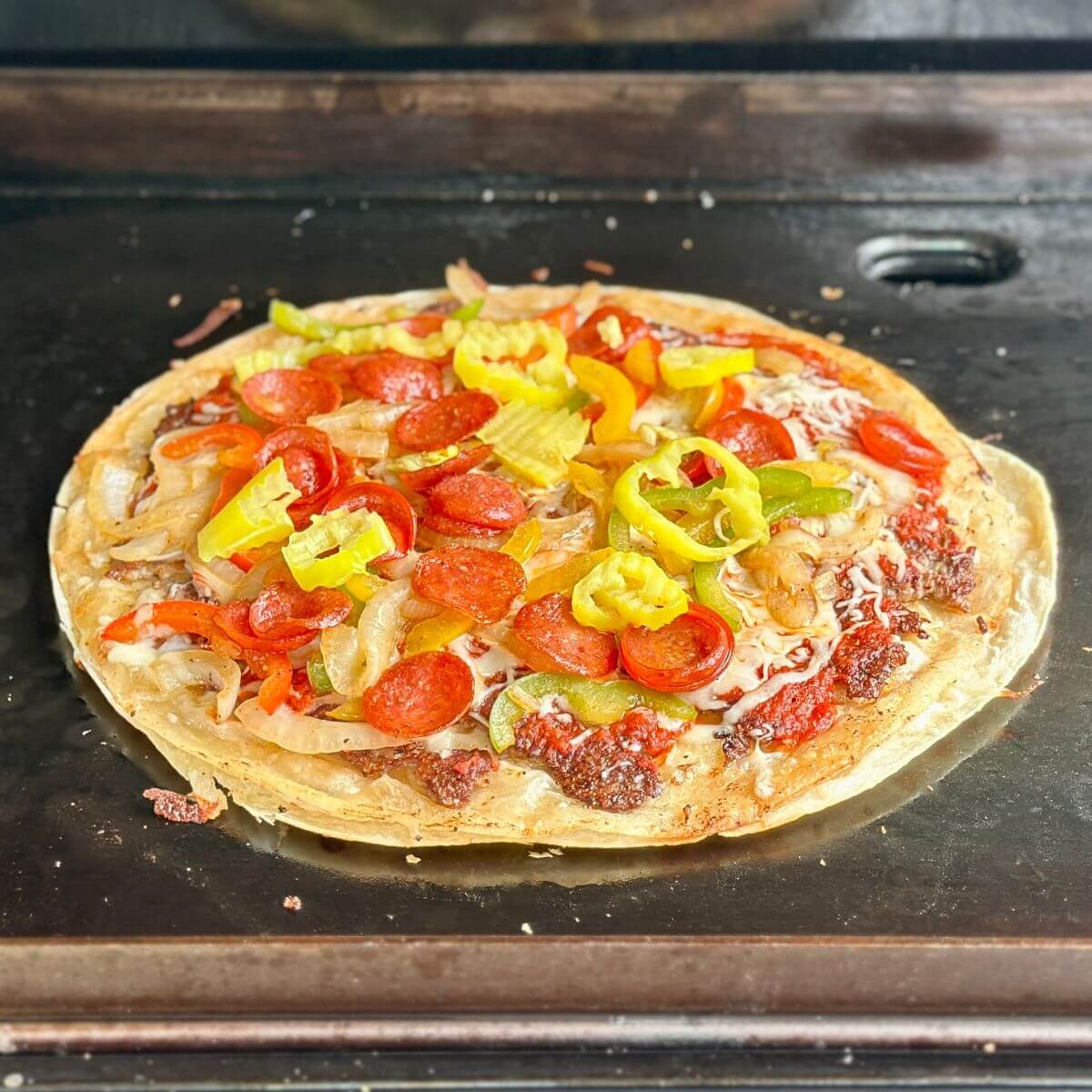 cooking a tortilla pizza on a Blackstone griddle