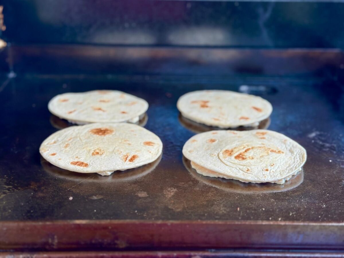 cooking chicken smash tacos meat side down on a griddle