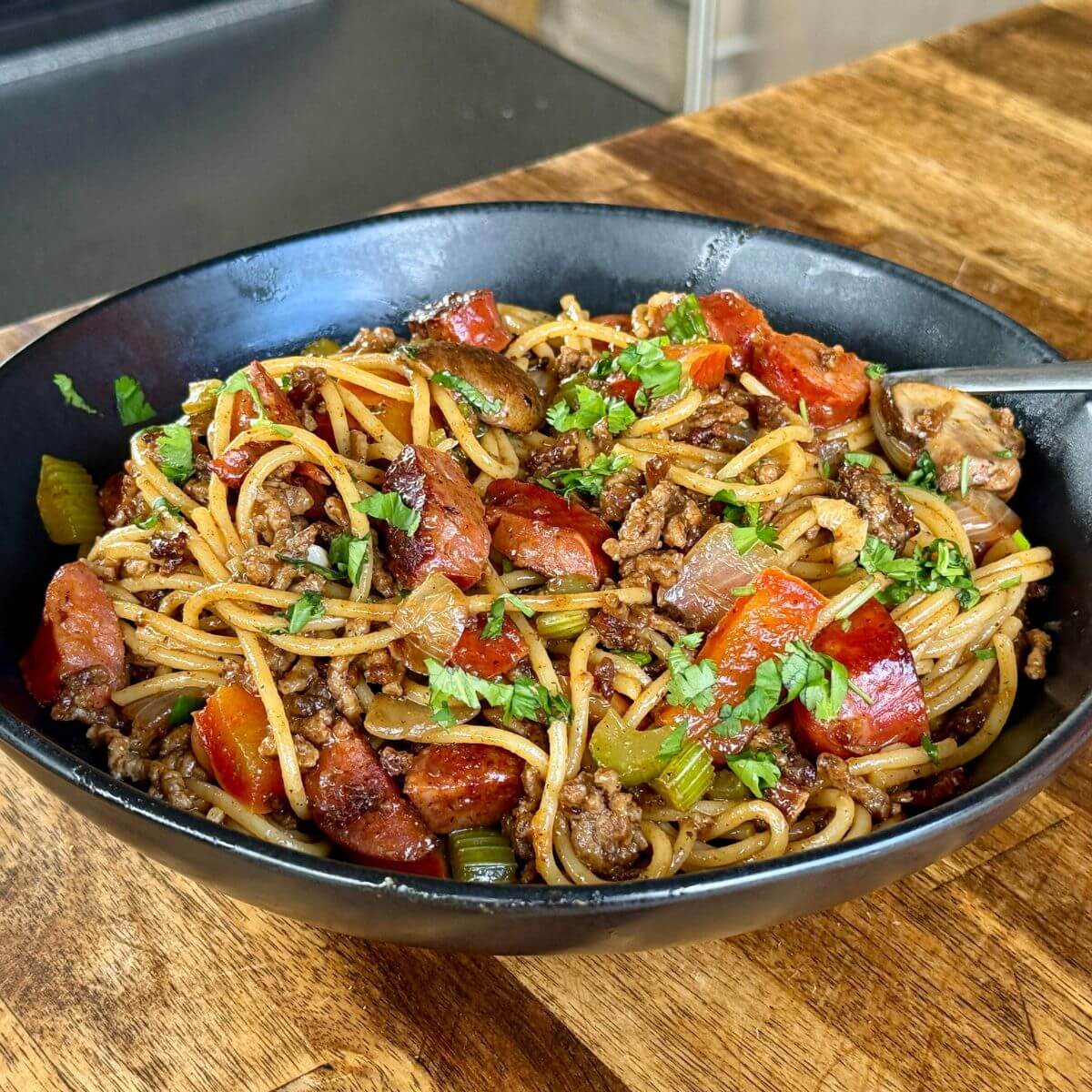 dirty spaghetti with ground beef, andouille sausage, and vegetables
