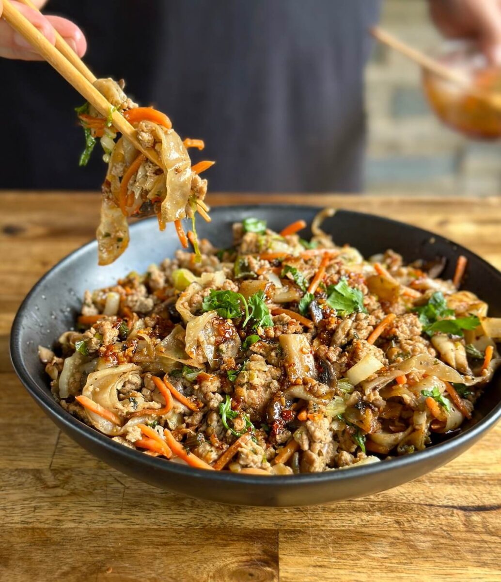 dumpling in a bowl with ground pork, wonton wrapper noodles, vegetables, and sauce