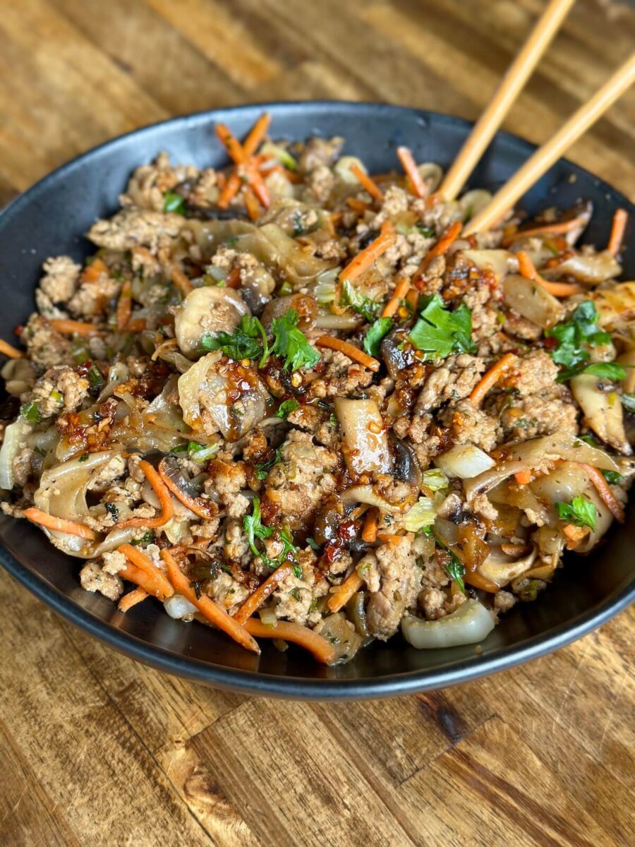 dumpling in a bowl with ground pork, wonton noodles, shredded carrots, and cilantro