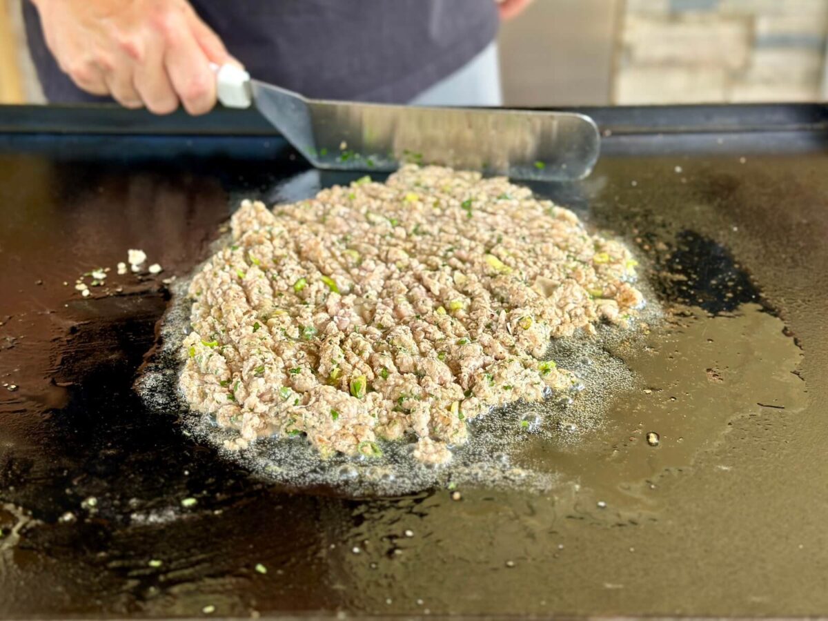 cooking ground pork and seasonings on a griddle