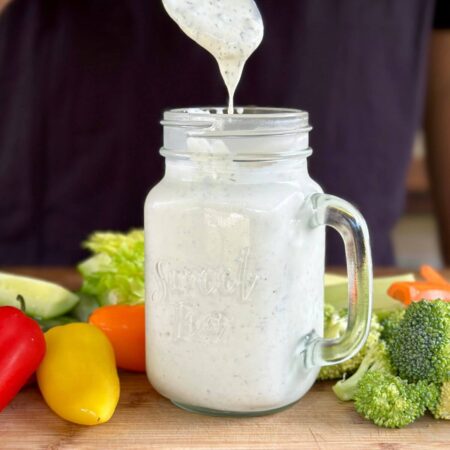 homemade buttermilk Ranch dressing in a jar with vegetables on a cutting board