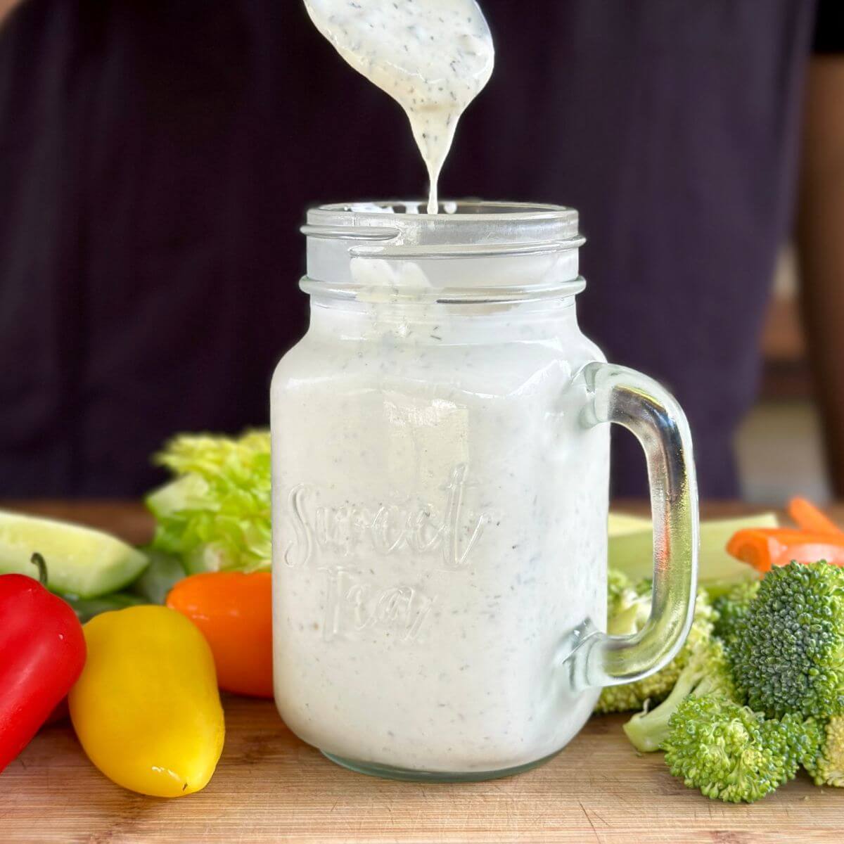 homemade buttermilk Ranch dressing in a jar with vegetables on a cutting board