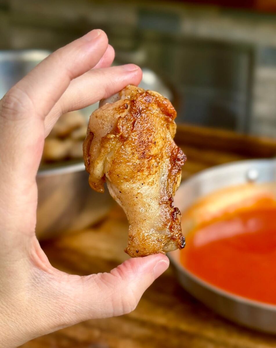 woman's hand holding a crispy chicken wing
