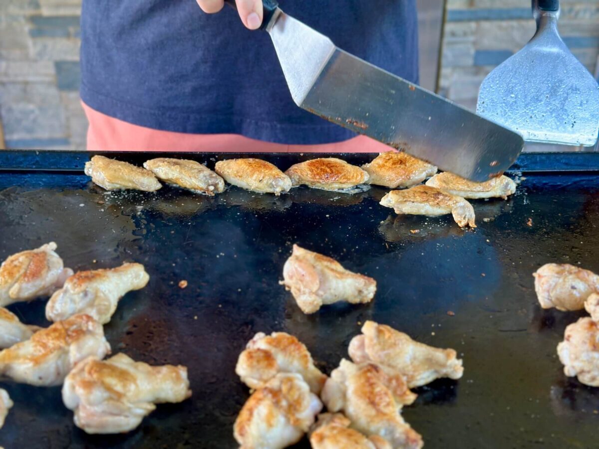moving chicken wing flats to the side edge of a Blackstone griddle while cooking