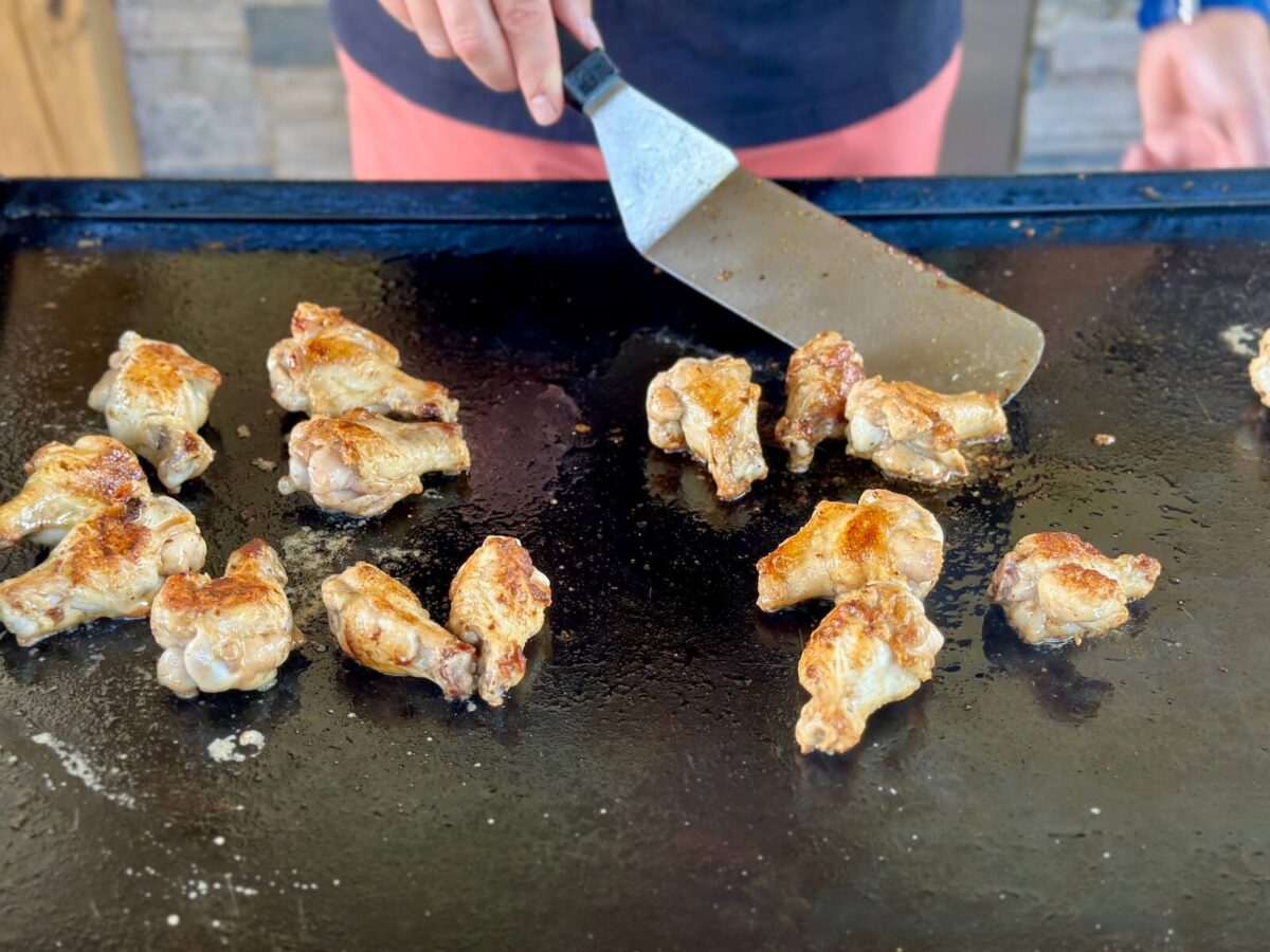 flipping crispy chicken wings on a Blackstone griddle
