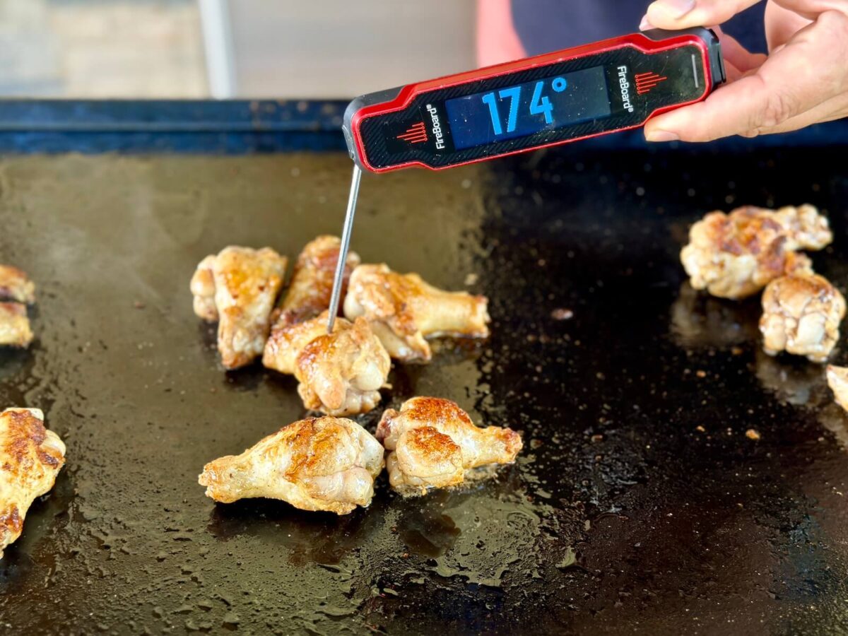 instant read meat thermometer that says 174 degrees F in a chicken wing on a griddle
