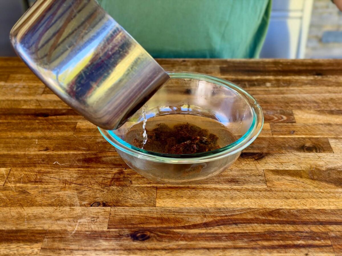 pouring water over pieces of tamarind paste in a bowl
