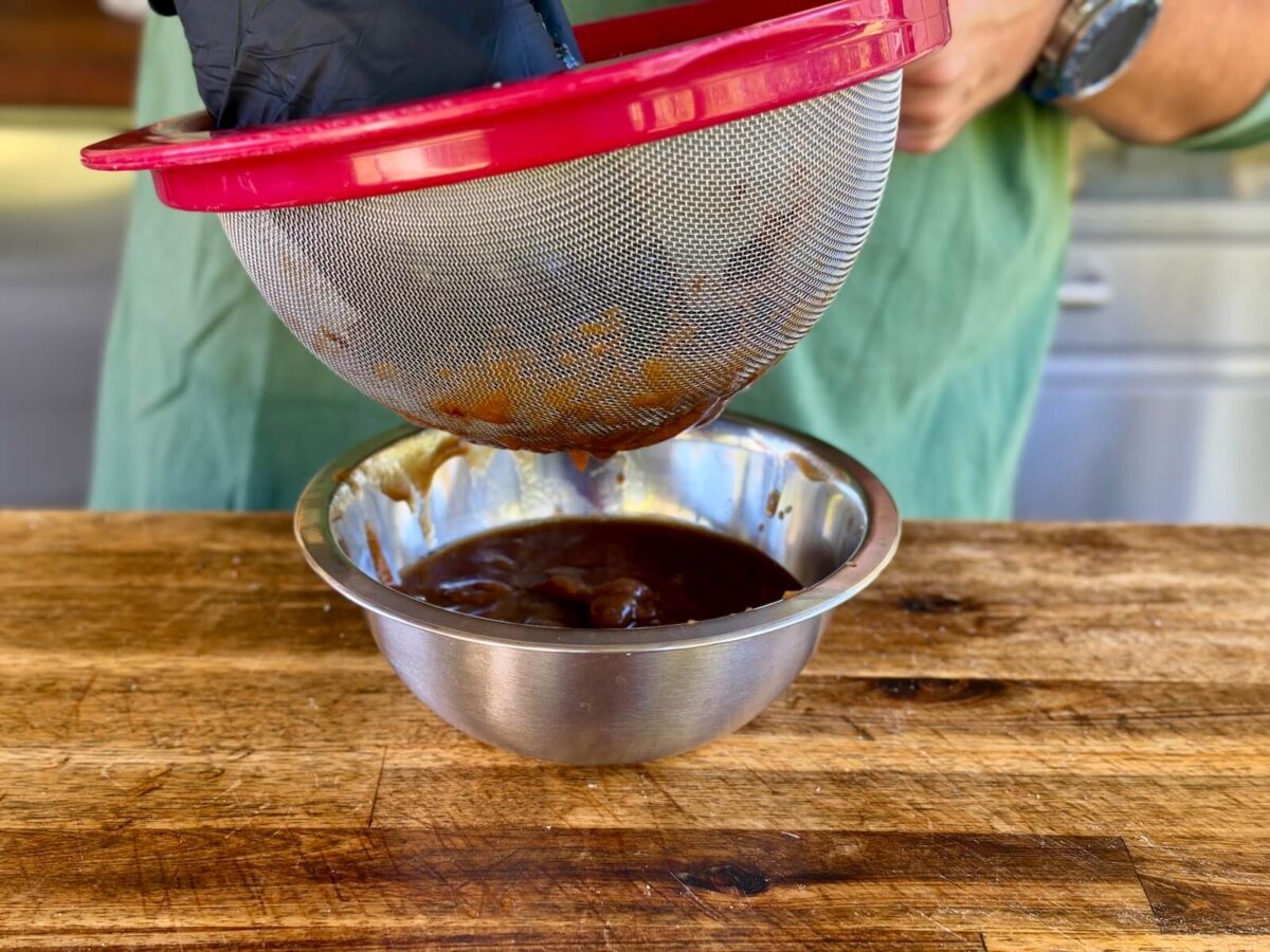 using a mesh strainer to strain tamarind paste